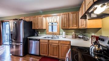 A kitchen with wooden cabinets, stainless steel appliances, and a window with curtains.