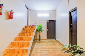 A wooden staircase leading to a door with a security camera above it. - Super Hotel O Jessore Road Kolkata (Barakpur)