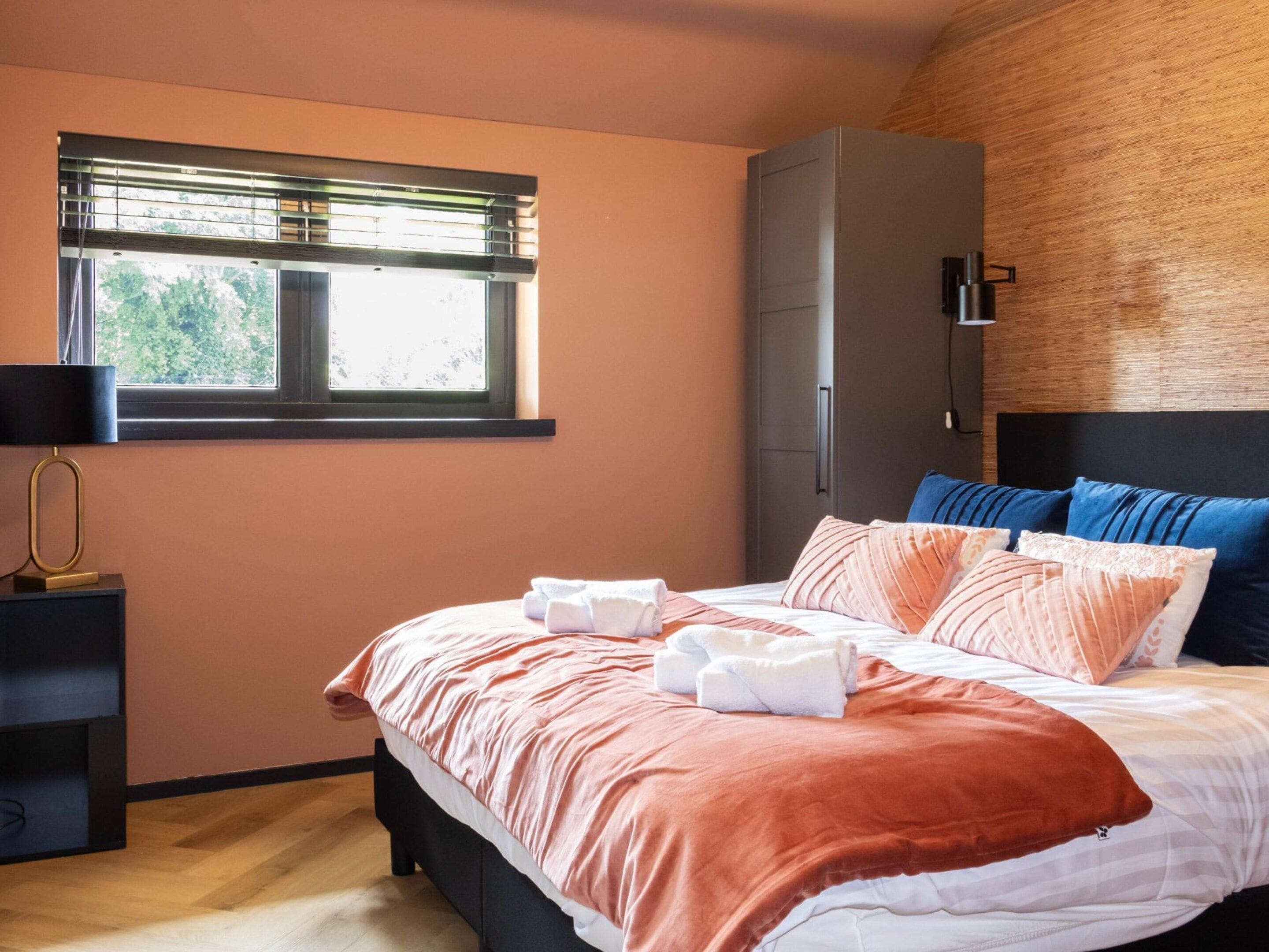 Une chambre à coucher comprenant un lit, une armoire, une table de chevet et une fenêtre avec des stores.