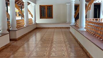 A spacious corridor with a patterned wooden floor, white columns, and a wooden ceiling.