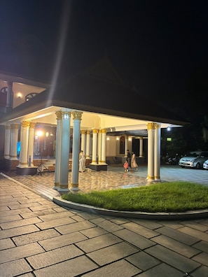 A hotel entrance with a covered patio area, columns, and a paved walkway.