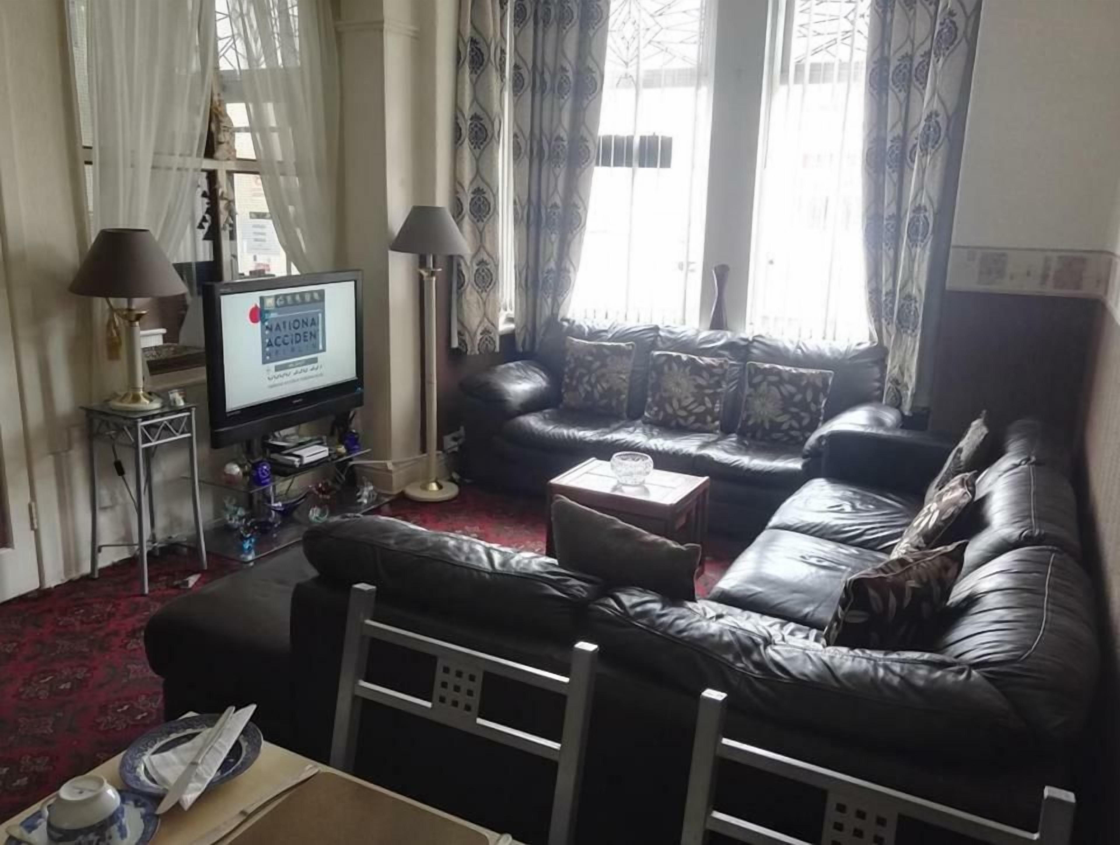 Una sala de estar con un sofá de cuero, un televisor y una mesita.