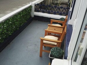 A balcony with a wooden chair and a potted plant. - White Moon Hotel (Blackpool)