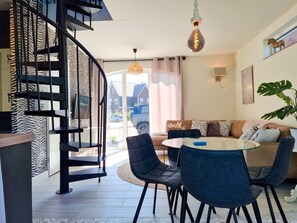 A modern living room with a spiral staircase, a round dining table, and a sofa. - Mb02 Holiday Home The Little Fox (Middelburg)