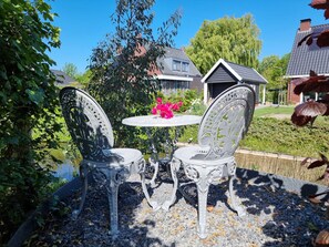 A patio with two ornate metal chairs and a small round table, surrounded by gravel and greenery. - Mb02 Holiday Home The Little Fox (Middelburg)