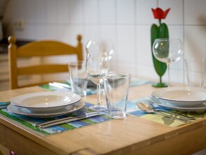 A dining table set with plates, glasses, and cutlery, with a chair in the background. - 9 in the Thomsen House (St. Peter-Ording)