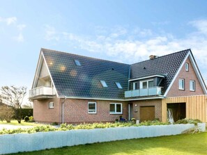 A modern two-story house with a sloped roof, a balcony, and a brick exterior. - 9 in the Thomsen House (St. Peter-Ording)