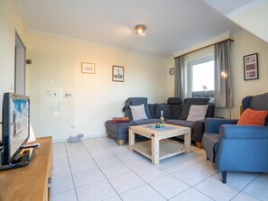 A living room with two sofas, a coffee table, and a television on a wooden stand. - 9 in the Thomsen House (St. Peter-Ording)