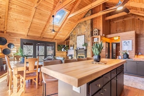 A wooden interior with a high ceiling, a stone wall, and a dining area with a wooden table and chairs. - Licklog Lodge (Ellijay)