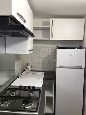 A kitchen with a gas stove, white cabinets, and a white refrigerator. - Apartment located in Maiori on the Amalfi Coast with a large panoramic terrace (Maiori)