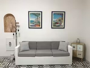 A modern living room with a white sofa, two framed artworks on the wall, a wooden archway, and a patterned floor. - Apartment located in Maiori on the Amalfi Coast with a large panoramic terrace (Maiori)
