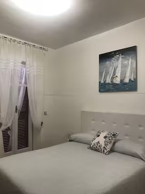 A bedroom with a bed, a painting of sailboats, and a window with curtains. - Apartment located in Maiori on the Amalfi Coast with a large panoramic terrace (Maiori)