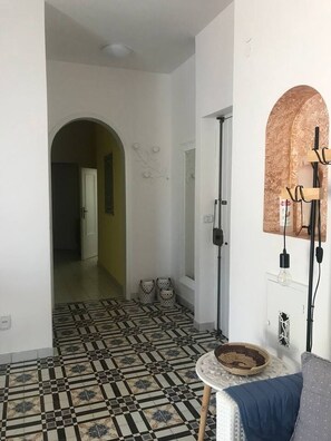 A hallway with patterned flooring, a round table with a woven basket, and a wall-mounted light fixture. - Apartment located in Maiori on the Amalfi Coast with a large panoramic terrace (Maiori)