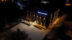 Un bâtiment moderne, avec une enseigne lumineuse indiquant « Rest & More by DEDEMAN » la nuit.