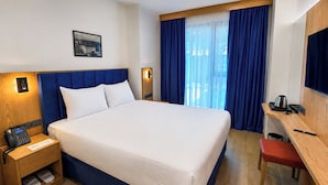 A hotel room with a large bed, a desk with a chair, a small table with a kettle, and a nightstand with a phone. - Rest&More Dedeman Sakarya Erenler (Erenler)