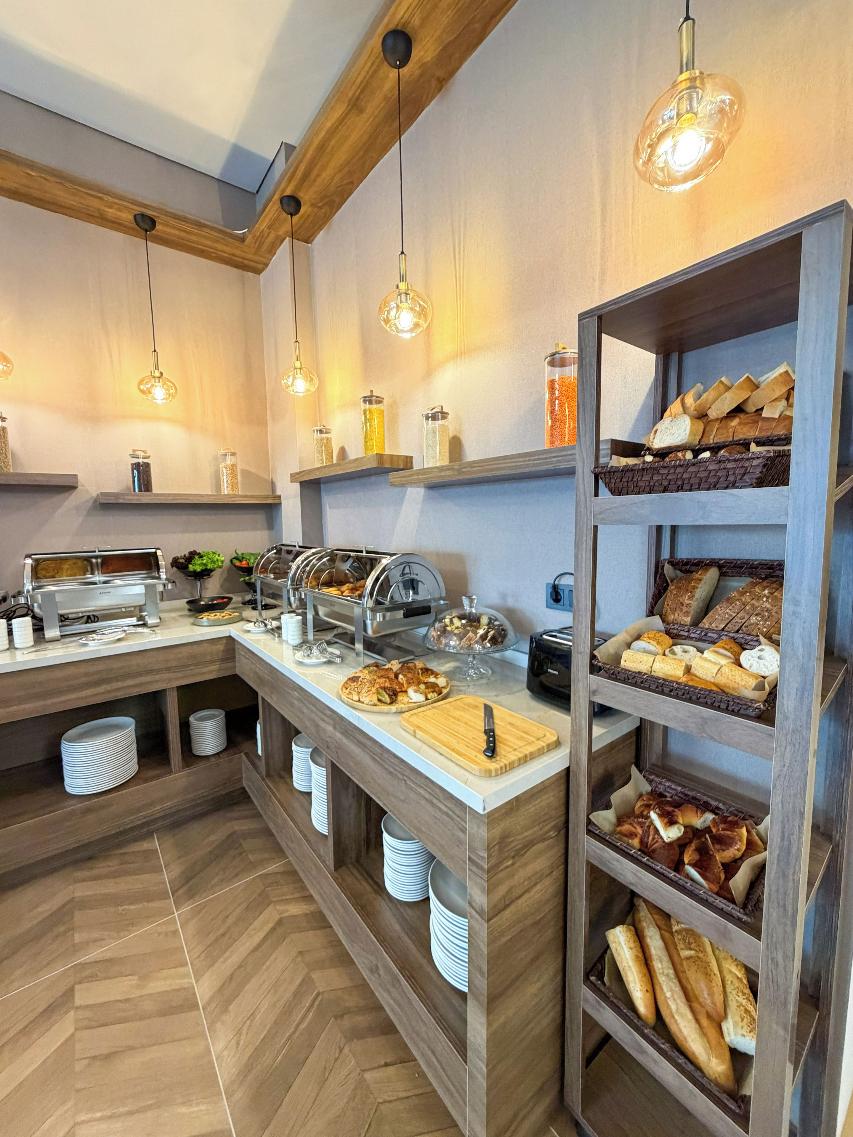 Disposición de buffet con diferentes alimentos, fuentes de servicio y un cuchillo sobre tabla de cortar.