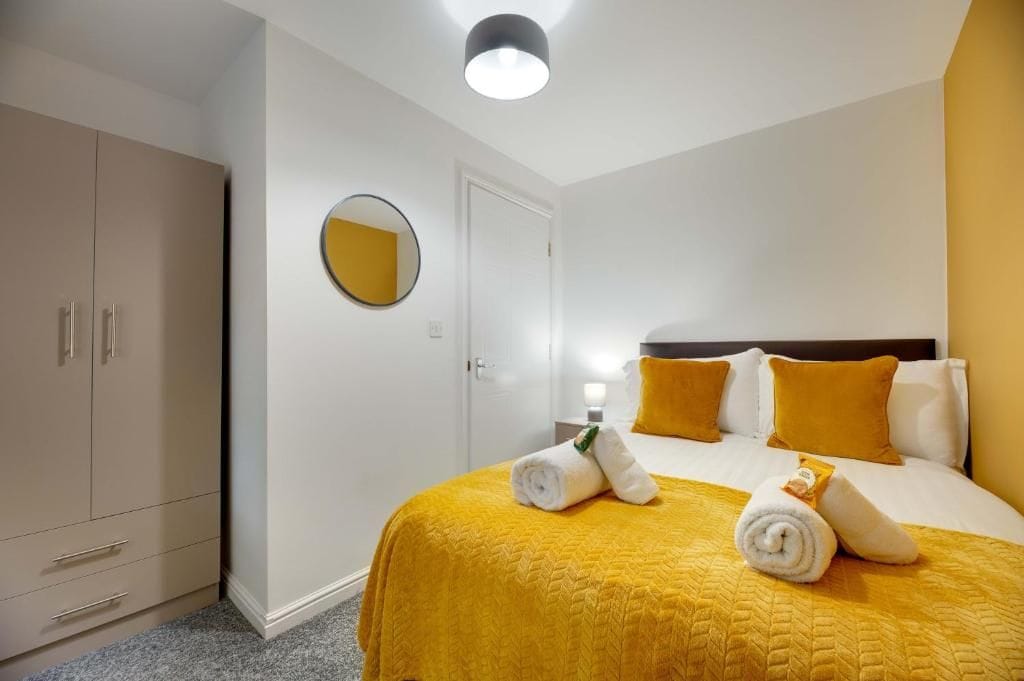 Hotellihuone, jossa on sänky, vaatekaappi, peili ja ovi.