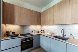 A modern kitchen with wooden cabinets, a built-in oven, and a stainless steel sink. - Otium Lake Como by MyHomeInComo (Como)