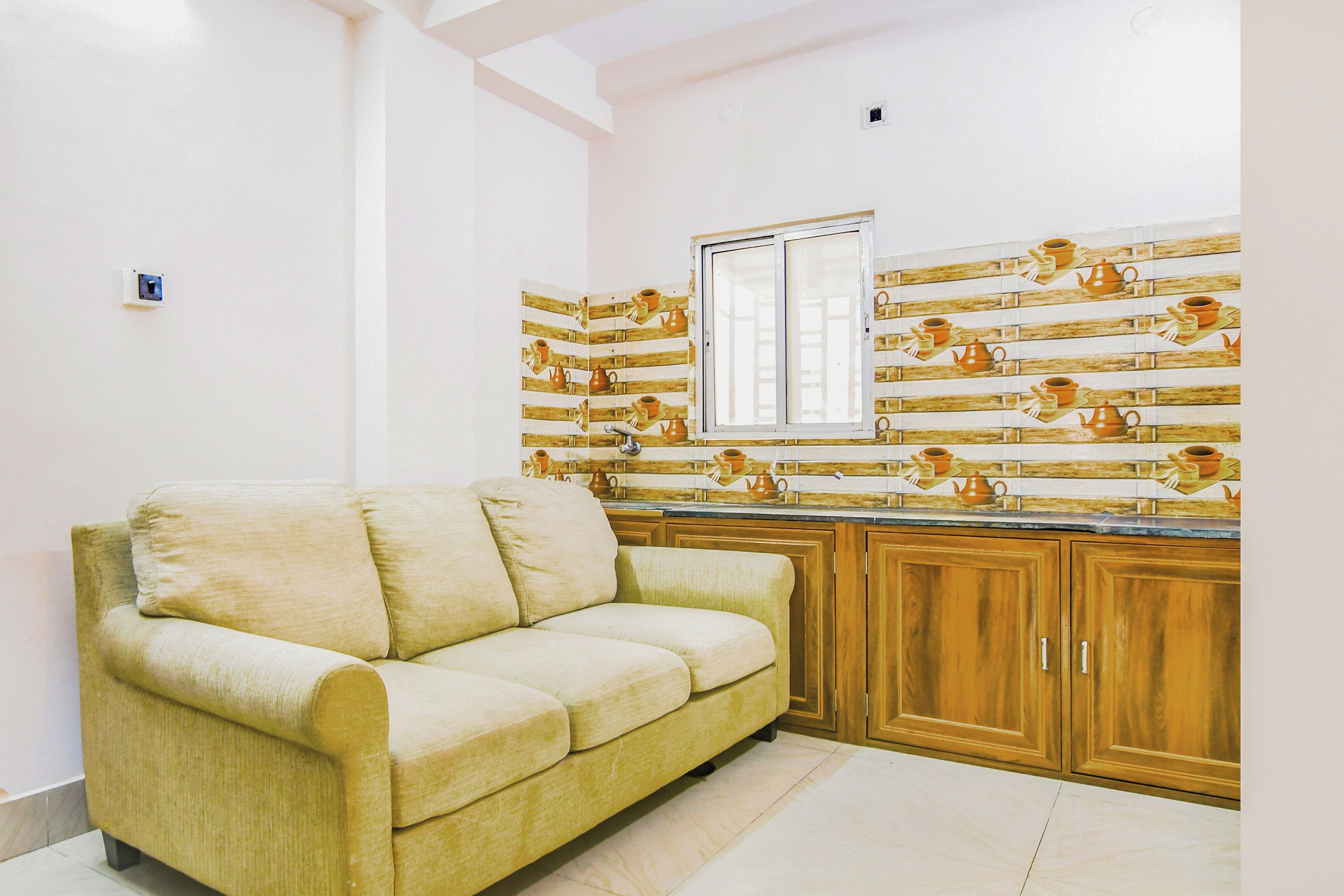 Una sala de estar con un sofá y una cocina con armarios de madera y un ventanal.
