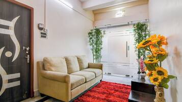 A modern hotel lobby with a beige sofa, a red rug, and a vase of sunflowers.