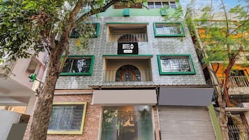 Un edificio con un letrero que indica que es un hotel, con fachada de piedra, varias ventanas con marcos verdes y una entrada visible.