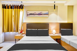 Hotellihuone, jossa on suuri sänky, kaksi yöpöytää, yölamppu, seinään kiinnitetty valaisin ja taulu sängyn yläpuolella.