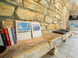 A stone wall with books and a framed picture on a shelf. - Ground Floor in the Jan Mayen House (St. Peter-Ording)