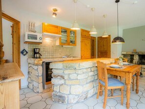 A kitchen with a stone island, wooden cabinets, a microwave, and pendant lighting. - Ground Floor in the Jan Mayen House (St. Peter-Ording)