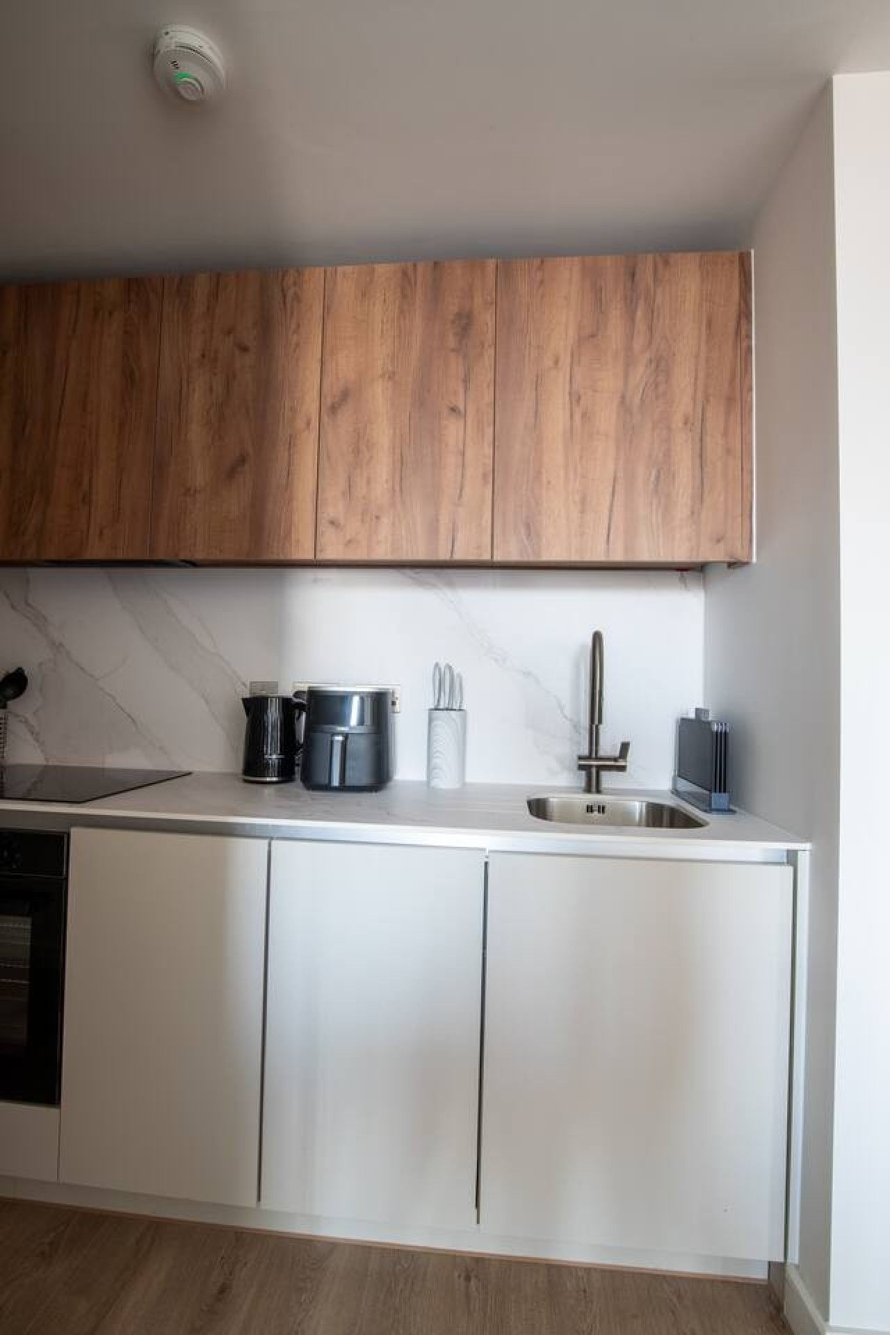 A modern kitchen with wooden cabinets, a stainless steel sink, and a built-in oven.