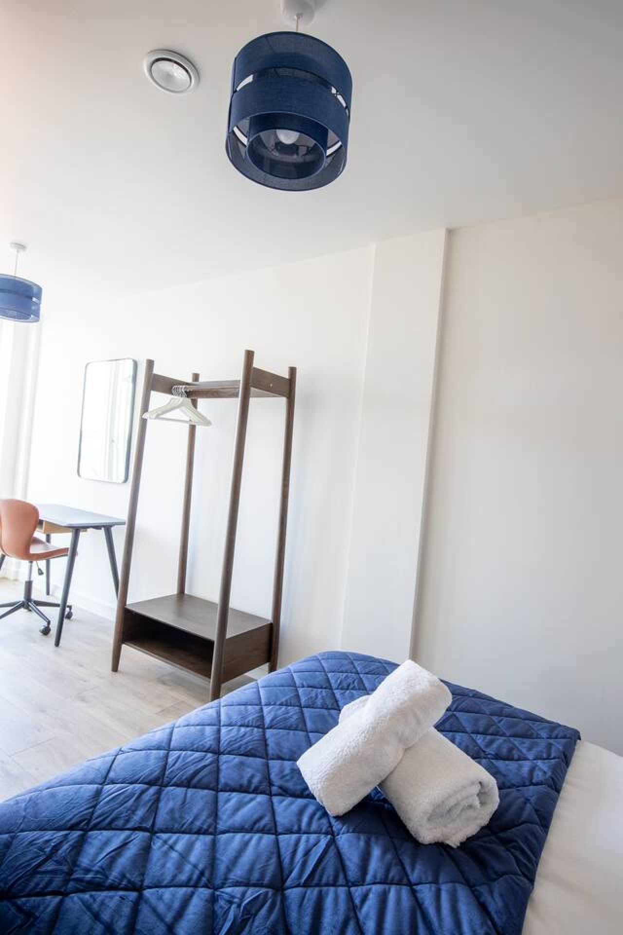 A bedroom with a bed, a desk, and a chair.