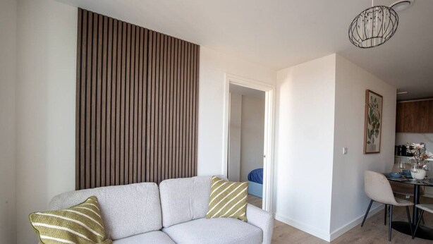 Una sala de estar moderna con un sofá, una mesa de comedor con sillas y una cocina al fondo.