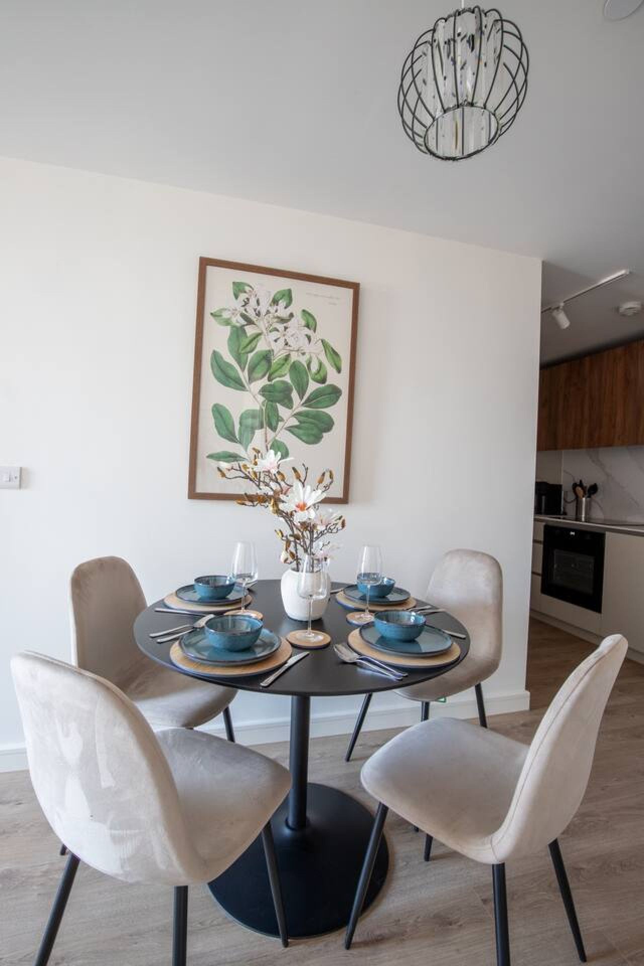 A dining area with a round table, six chairs, and a vase with flowers.