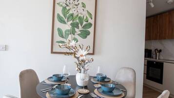 A dining area with a round table, six chairs, and a vase with flowers.