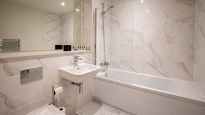 Un baño moderno con una bañera independiente, un lavabo y un box de ducha con mampara de vidrio.