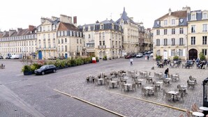 A cobblestone square with outdoor seating, historic buildings, and a few parked cars. - The Charm of Place Saint-Sauveur (Caen)