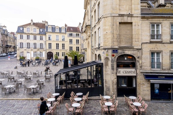 Een café met terras aan een geplaveid straatje, omringd door historische gebouwen.