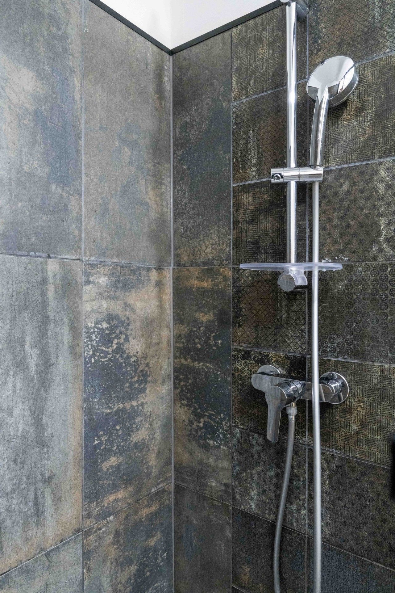 A shower with a chrome faucet and a handheld showerhead.