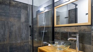 A modern bathroom with a glass-enclosed shower, a wooden vanity, and a large mirror. - The Charm of Place Saint-Sauveur (Caen)