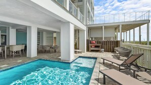 Ein Poolbereich mit Whirlpool, Sitzgelegenheiten im Freien und einem Grill.