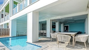 Un espace aménagé au bord de la piscine, comprenant une piscine, des sièges extérieurs et un patio couvert.