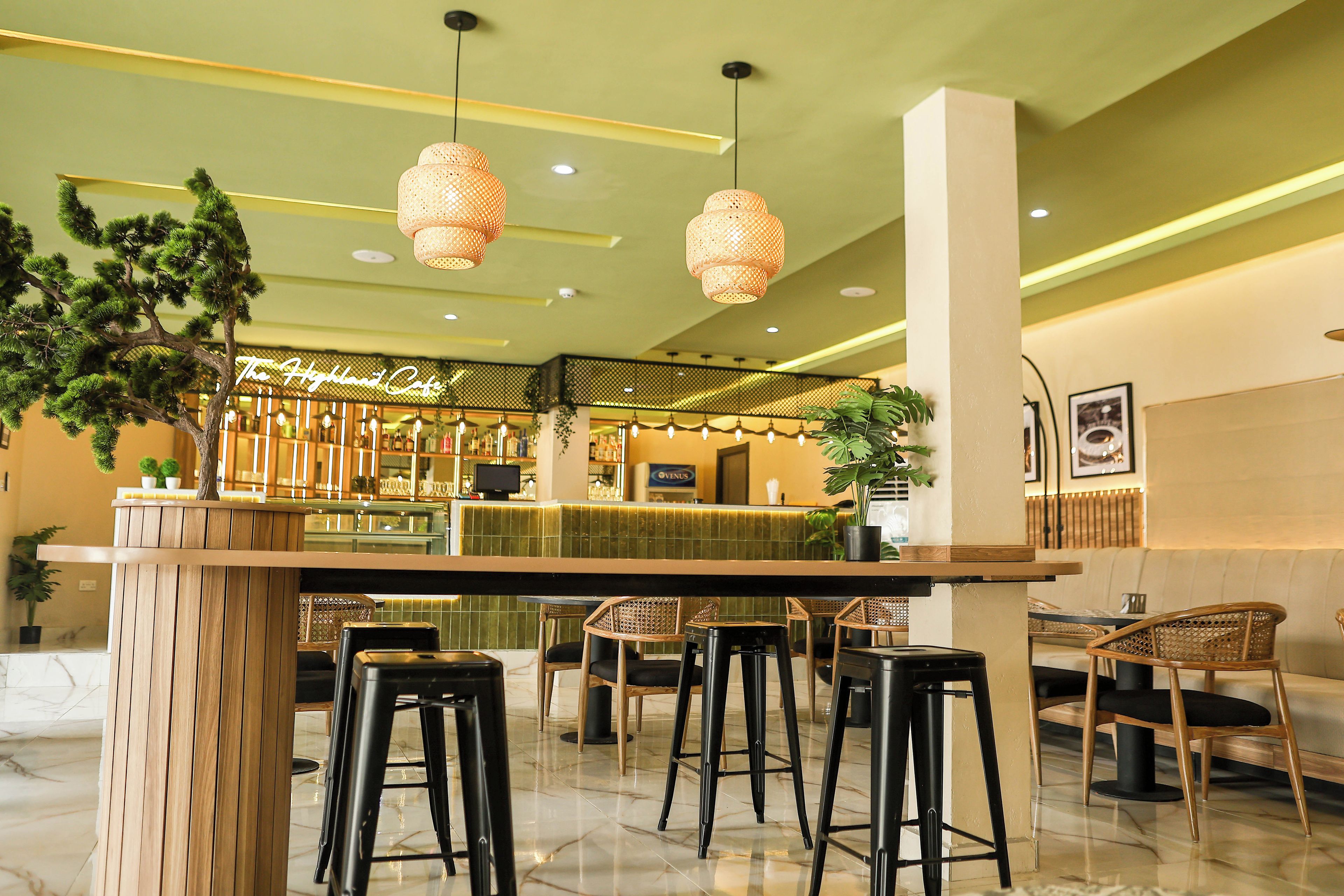 Una zona de bar con mostrador, taburetes e iluminación colgante.