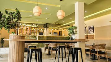 Una zona de bar con mostrador, taburetes e iluminación colgante.