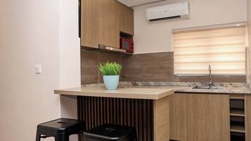 Una cocina moderna con armarios de madera, encimera de mármol, una pequeña planta en maceta y un taburete negro.