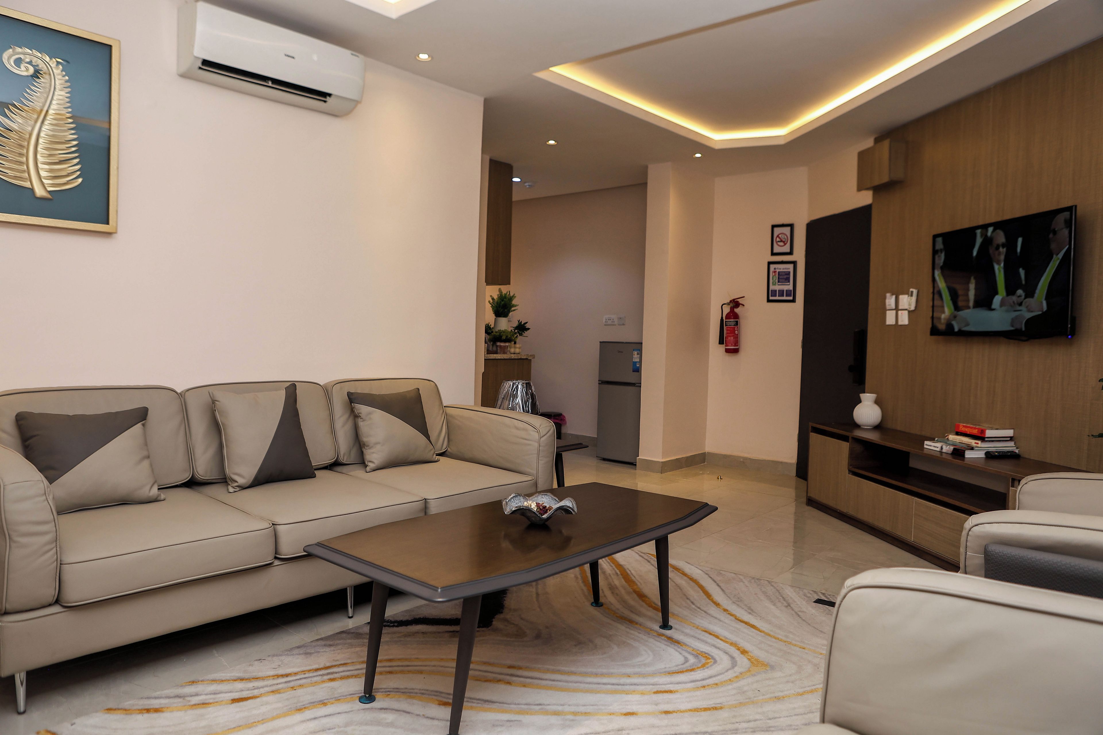 Una sala de estar moderna con un sofá, una mesa de centro y un televisor de pantalla plana montado en la pared.