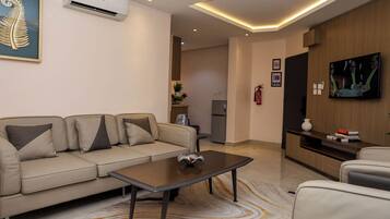Una sala de estar moderna con un sofá, una mesa de centro y un televisor de pantalla plana montado en la pared.