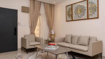 Una sala moderna con un sofá, sillones, una mesa de centro y decoración en la pared.