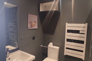Een badkamer met een witte wastafel, een toilet, een handdoekhouder en een spiegel aan de muur.