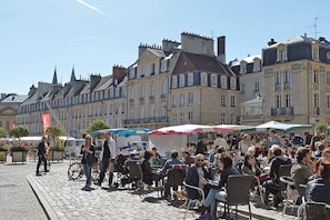 Een geplaveid straatje met terrasjes, historische gebouwen en een heldere lucht.