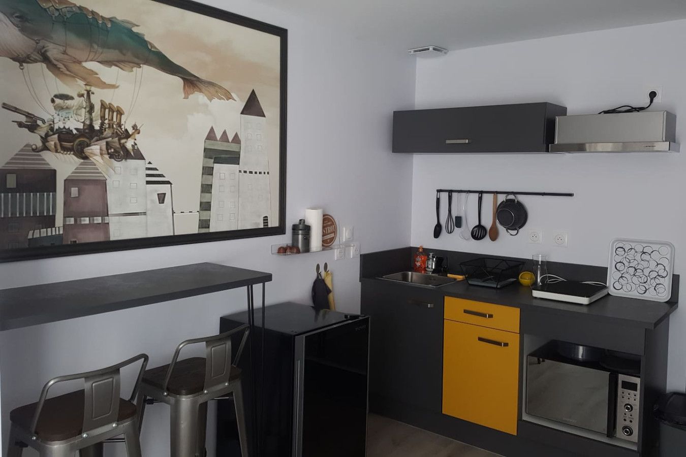 Une cuisine moderne équipée d’un lave-vaisselle, d’un four à micro-ondes et ornée d’un tableau représentant un paysage urbain.