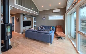 Ein modernes Wohnzimmer mit einer Couch, einem Liegesessel, einem Fernseher und einem Kamin.